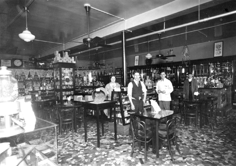 Previously the home of the I.O.O.F., the Post Office and Watt's Drugs, it was Lobraico's Rexall Drugs for sixty-six years. It is now Chelsea's. Ivy (Opal Wilson) Lobraico is behind the counter in the center, also pictured is Cal Hughey.