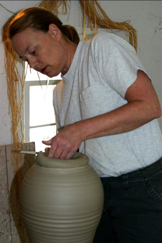 Sandi Finney finishes the rim of a large vase.
