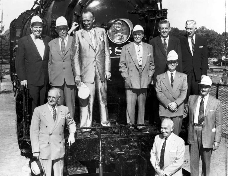Original caption: You are looking at several hundred thousand dollars worth of railroad leadership in this photo. After these gentlemen departed, it became the kids' turn to play. (Rear row, l - r: Mayor Alex Clark, Wayne A. Johnson, President, ICRR; Warren Brown, Monon; Chas. Nauh, President, Ind'pls Belt-Stockyards Co.; Ike Duffy, President, Central Indiana Railroad; and H.H. Pevler, V.P., Pennsy. Front Row: H. Raffensperger, Director, DPR; C. Walter McCarty, editor, Ind'pls. News; S.P. Hutchison (behind McCarty), the last engineer to run 587; and Lynne L. White, Chairman, NYC&StL R.F. (Nickel Plate).