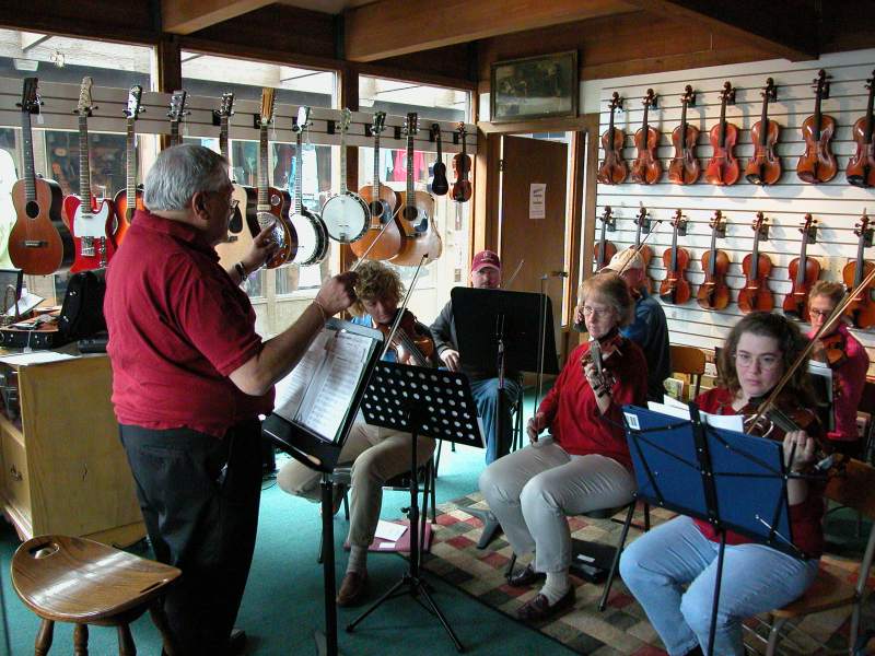 Stefan Argyelan conducts the SOS (Students of Stefan) Ensemble at the grand opening of Frank's Violins. Stefan has been the strolling violinist at Chanteclaire Restaurant for 30 years.