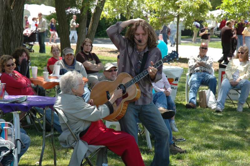 Guitarist Michael Kelly was all over the crowd during his performance on the 100.9FM Cafe Stage. Above, a woman in the audience strummed during a one of Michael's songs. On another song, Michael played his guitar with the help of an overturned table.