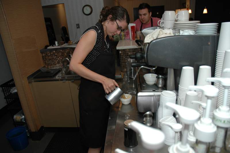 Mark watches as Katie pours the foam onto the latte.