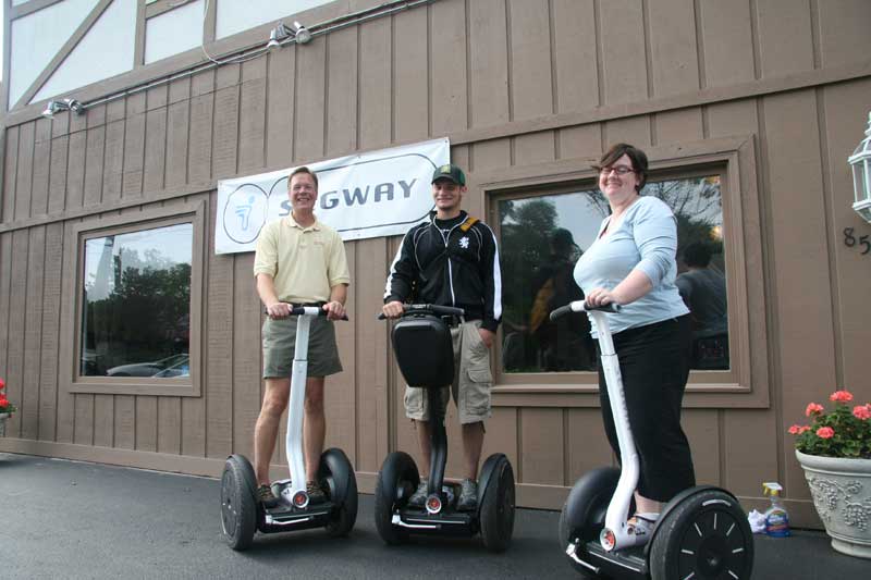 President Christopher Moyer, tour guide Joe Coombs and store manager Nora Morris pose on Segways in front of the new show room on 63rd Street