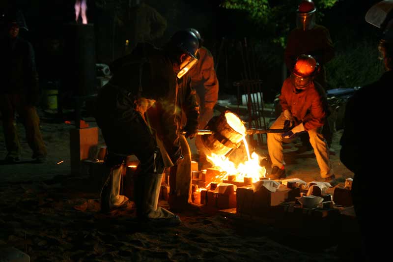 Pouring 2800 degree iron into the molds lined up in the sand at the Art Center
