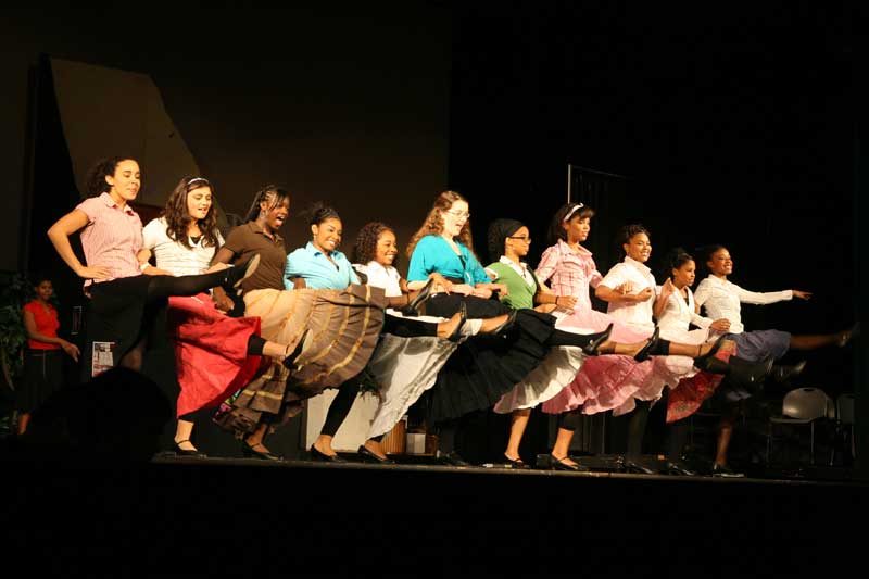 Colleen Friedly (center, blue shirt) as Vanessa Vegas and Ashley Moore (center green shirt) as Georgia Washington with the chorus.