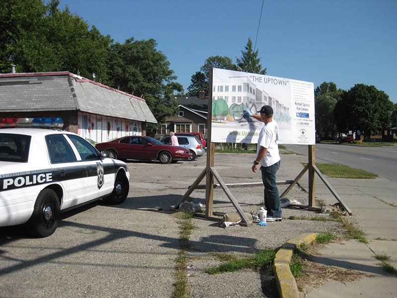 IMPD officer Henry Castor removing grafitti at 49th and College Avenue.