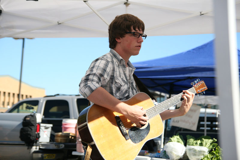 Evan Slusher playing guitar near the center of the market.