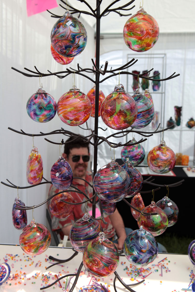 Doug Sweet of Karuna Glass behind a tree of ornaments.