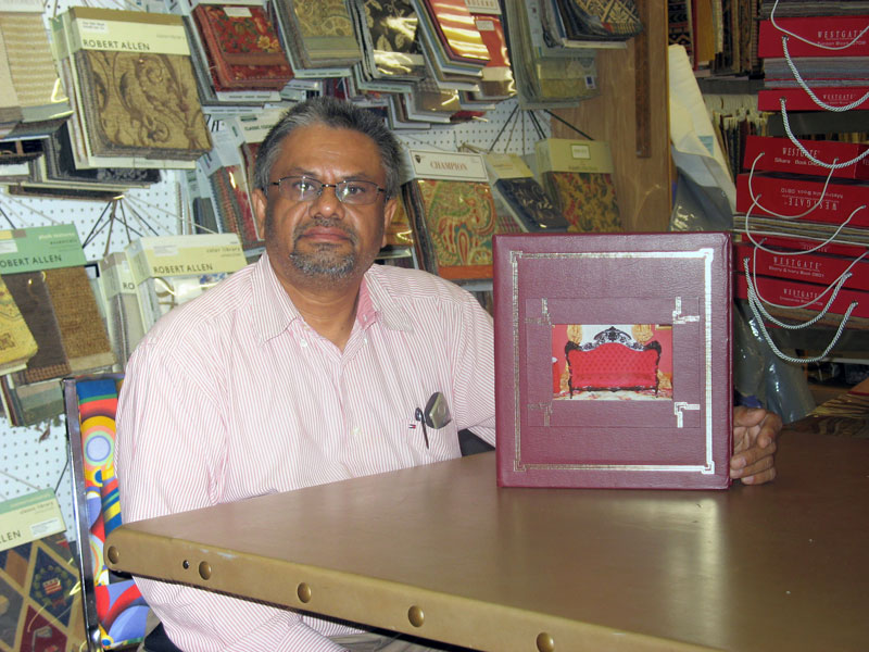 Trikam Parmar of Artcraft Upholstering displays a book of his work.