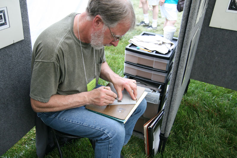 Printmaker Ken Swanson from Wisconsin carves linoleum blocks, makes 10 impressions, hand paints the prints, then frames the original block with a B&W print and the final painted print. This shows that the block is out of service, assuring no more impressions will be pulled.