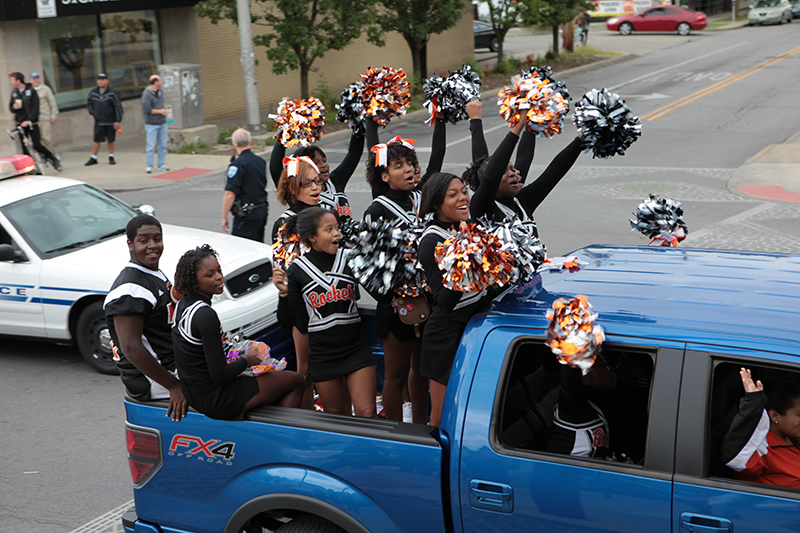 Cheerleaders waving to the faculty watching from the deck of 10-01 Food & Drink on Broad Ripple Avenue.