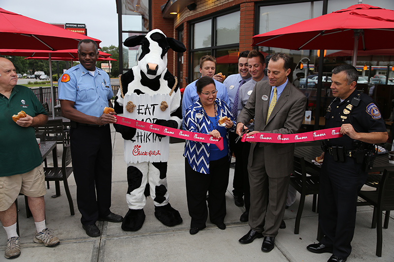 Jeff Mosely, Chick-fil-A franchise owner and his wife Leah cutting the ribbon at their new location in Broad Ripple. Jeff also owns Chick-fil-A at The Crossings location. Others in the front row left to right: resident Mike Somsel, IFD Station #32 Chief Gregg Harris, IMPD North District Commander Thomas Koppel.