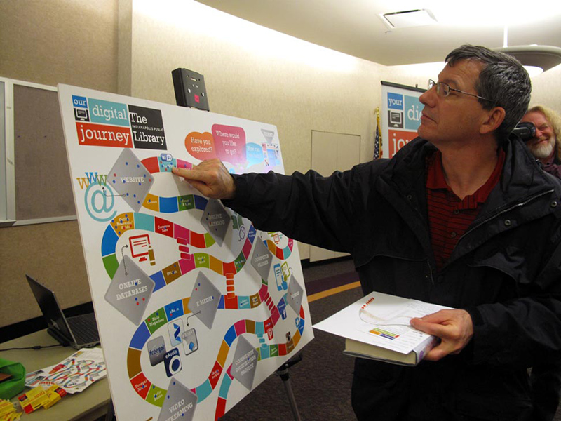 Glendale patron Dave Reifeis using a game board to indicate the types of digital activities he has done.