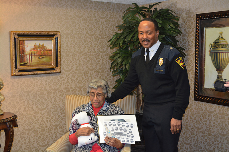 IFD Chief Ernest Malone gives Mrs. Wallace a photo, stuffed animal and picture showing Mr. Wallace's service in Co. 1.