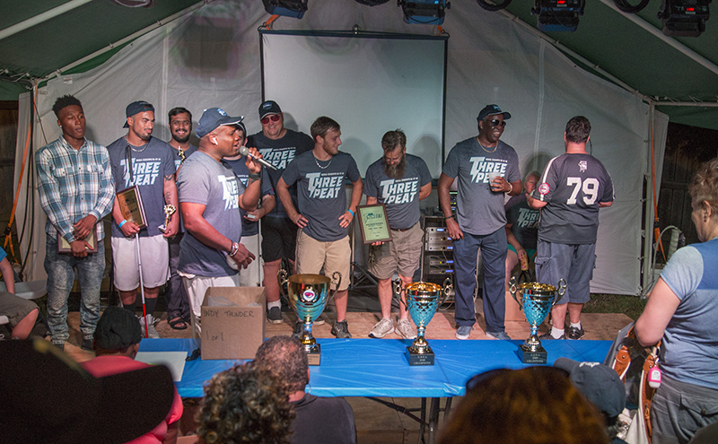 GM/Coach Darnell Booker (holding the microphone) handed out the team awards at the Pawn Shop Pub ceremony. The three World Series cups are on the table.