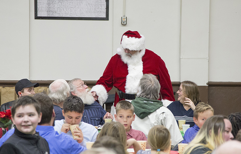 Santa examines the beard of a diner to compare it to his own.