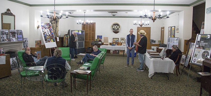 Seated by the fireplace is Rick Wilkerson, one of the Project's founders, and standing, facing the camera is Bruce Buchanan who is on the board of the Indiana Entertainment Foundation.