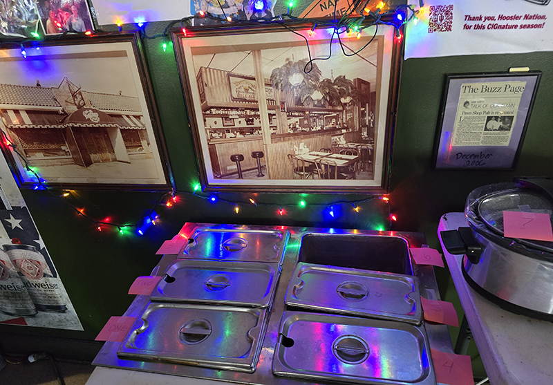 Some of the 10 chilis awaiting the judges under an old photo of the original Pawn Shop Pub on College Avenue.