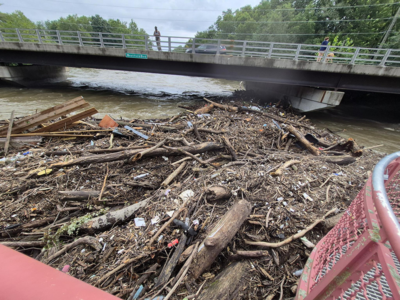 Debris coming down over the spillway at 73rd and Westfield piled up at the Monon Trail.